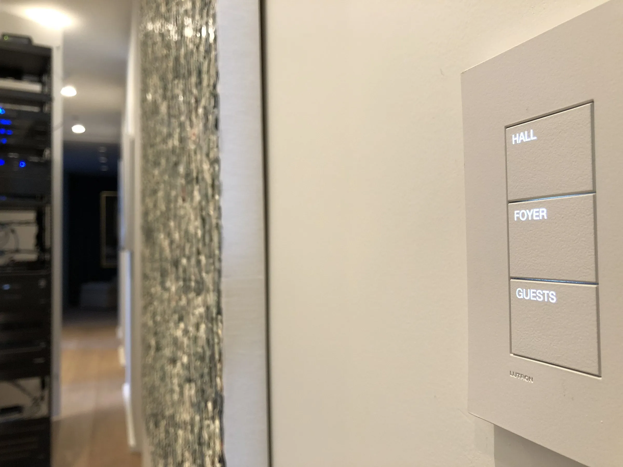 Engraved keypad labeled Hall, Foyer, and Guests beside a textured wall