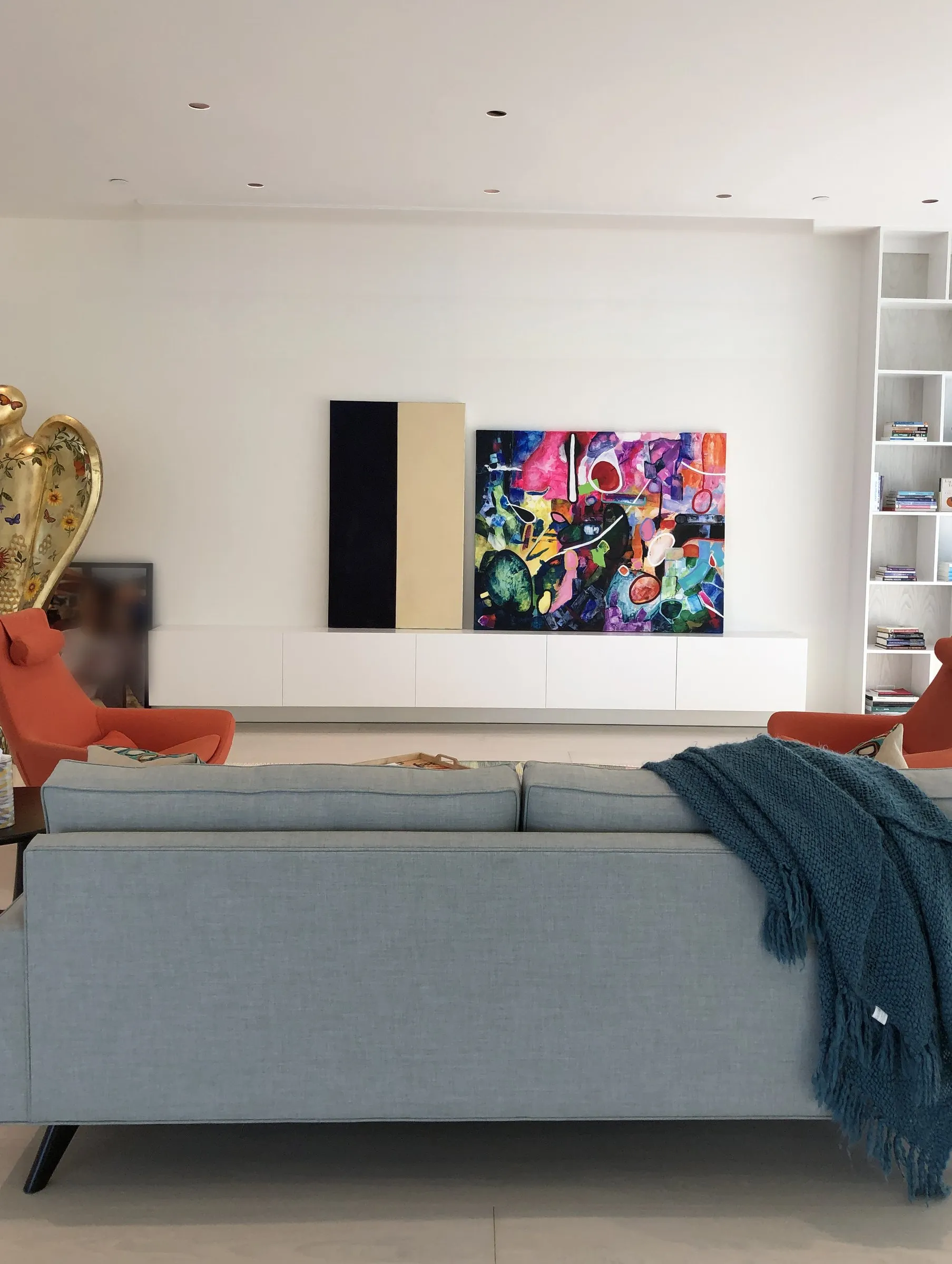 Bright living room with a colorful painting on a white wall under a plain flat ceiling